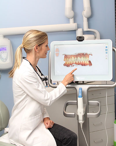 Dr. Julia pointing the screen that showing a simulation of teeth