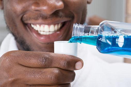 African American man pouring mouthwash after visit to Brush & Floss Dental Center in Stratford, CT