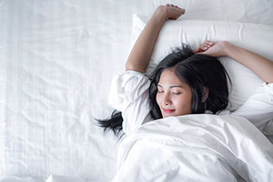 Woman waking up after a restful night’s sleep following her visit for sleep apnea at Brush & Floss Dental Center in Stratford, CT