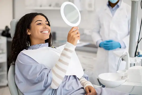 Beautiful Black patient looking in mirror and smiling at Brush & Floss Dental Center in Stratford, CT