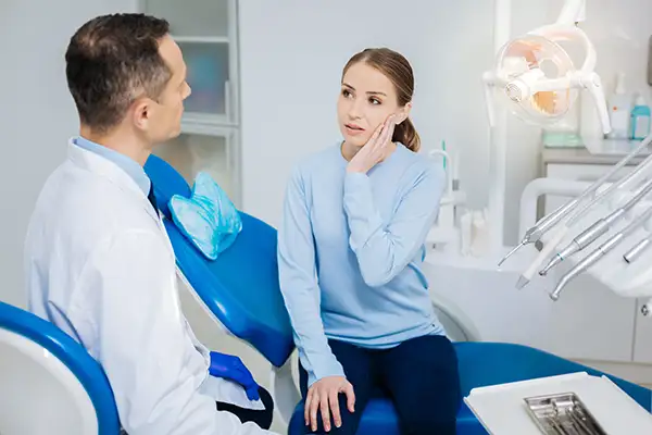 Concerned patient discussing her tooth pain with her dentist while sitting in a dental chair.