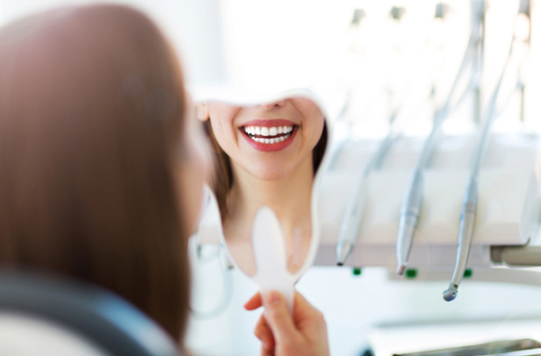 Woman looking at her smile in a mirror.