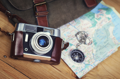 Image of a traveler's camera, map, and bag with oral hygiene products inside.